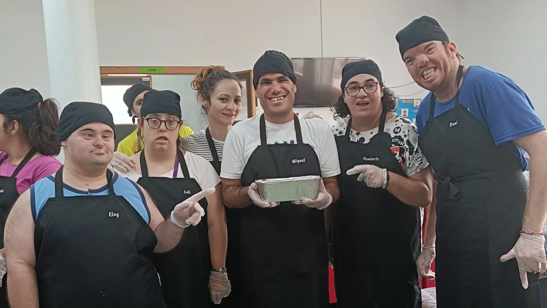 Grupo de personas con delantales participando en una actividad de cocina.
